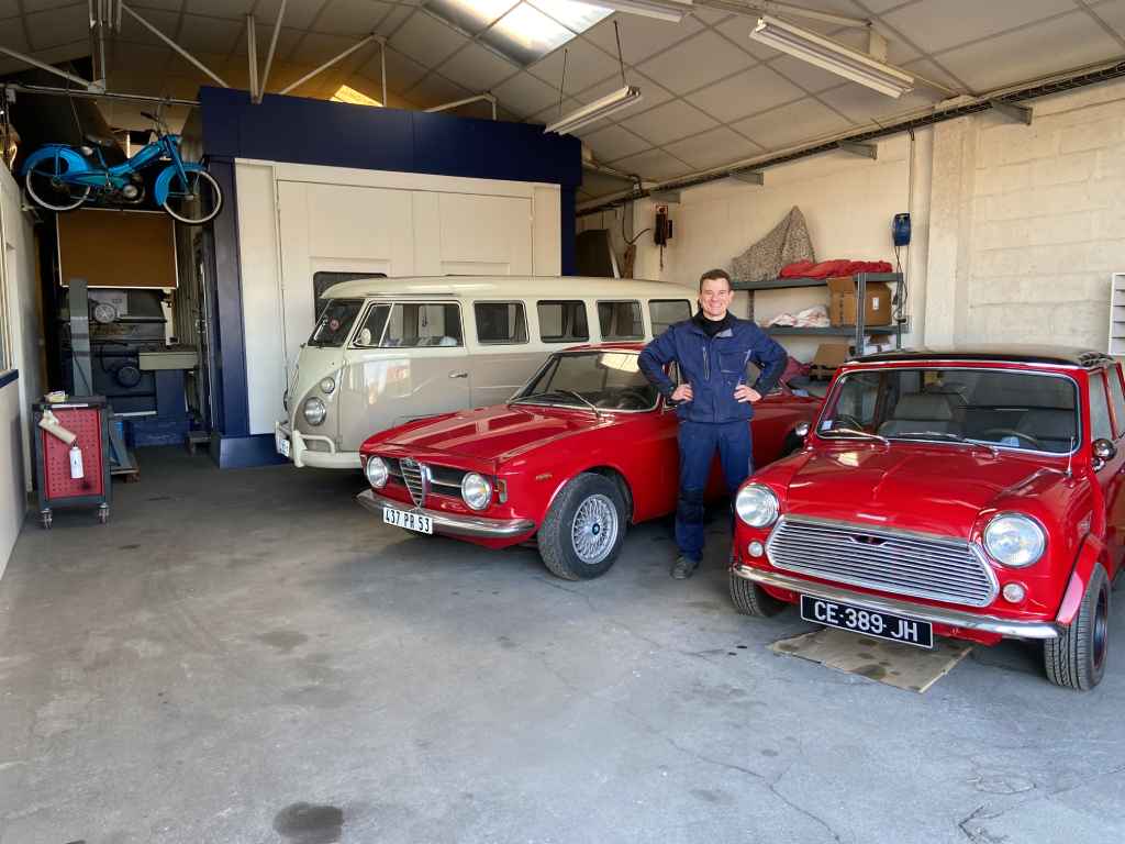 Jonathan, au milieu d'une Austin Mini, d'une Alfa Roméo Giulia, d'un Volkswagen Combi T1 et d'une mobylette